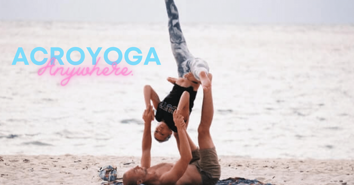 a fit couple practising acroyoga at teh beach.