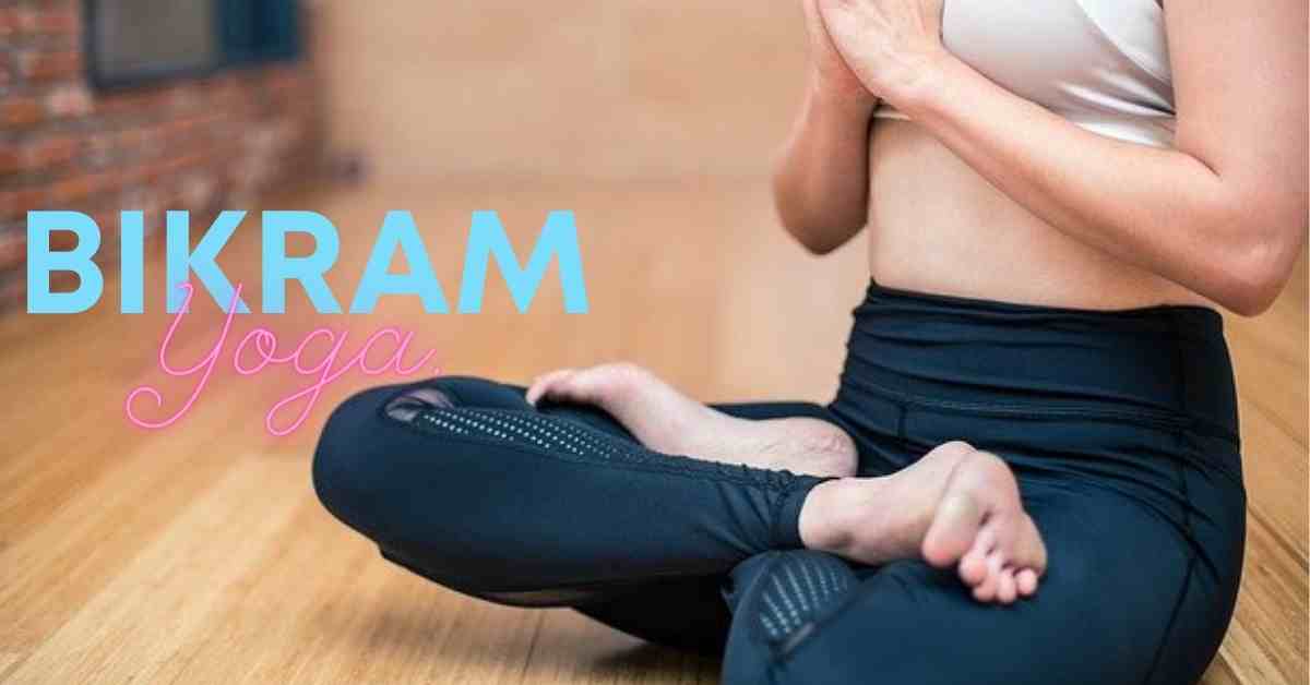 a woman wearing black yoga pants sitting cross legged practicing bikram yoga.